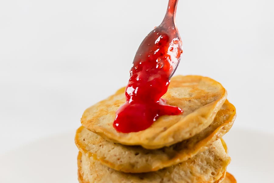 topping pancakes with a strawberry sauce using a spoon