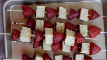 cake bites with strawberries on skewers in a pan