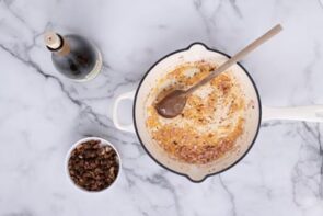 A white cast iron skillet with cooked shallot.