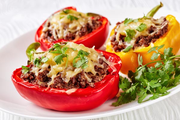 ground beef stuffed inside red and yellow bell peppers and topped with melted cheese