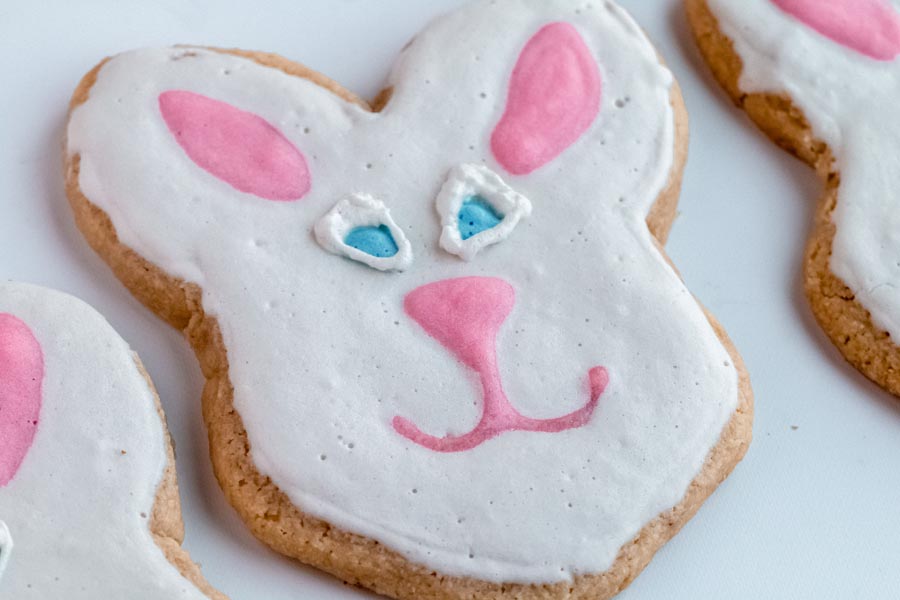 a sugar cookies decorated as a white bunny with pink ears and smile