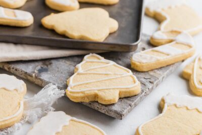 A thick sugar cookie decorated with white icing next to a bunch of other Christmas sugar cookies.