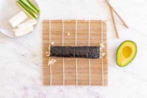 A rolled sushi roll on a bamboo mat.