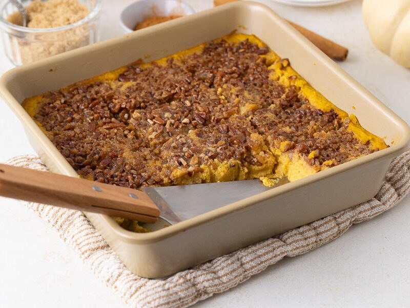 Keto sweet potato casserole with a golden pecan topping and serving spatula.