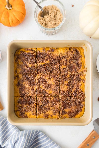 Top-down image of the casserole sliced into 9 pieces with a jar of brown sugar substitute and mini pumpkins in the background.