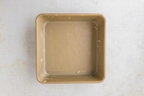 A square baking pan greased with butter, ready for batter.