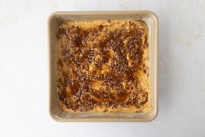 Casserole topped with a textured brown pecan crumble layer before baking.