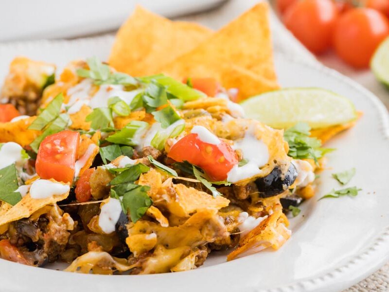 a plate with cheesy taco meat, tomato, cilantro, green onions and black olives