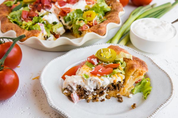 loaded keto taco pie with cheese, lettuce and tomato next a taco pie slice
