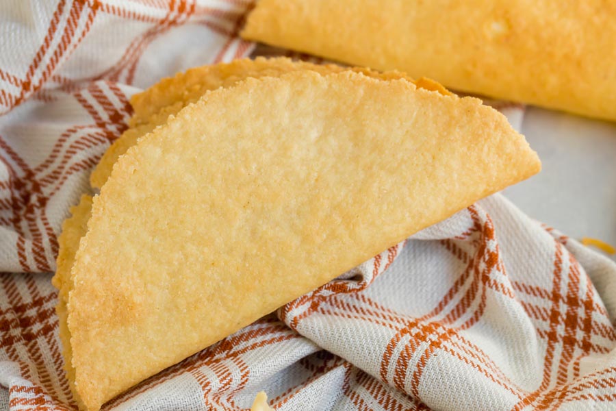 a hard shell taco on a plaid orange and cream napkin