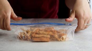 female hands holding a ziploc bag and coating takis