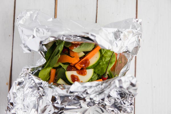 a foil packet filled with vegetables and spicy garlic sauce