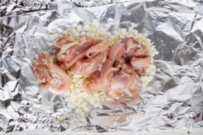 raw chicken on top of cauliflower rice on foil