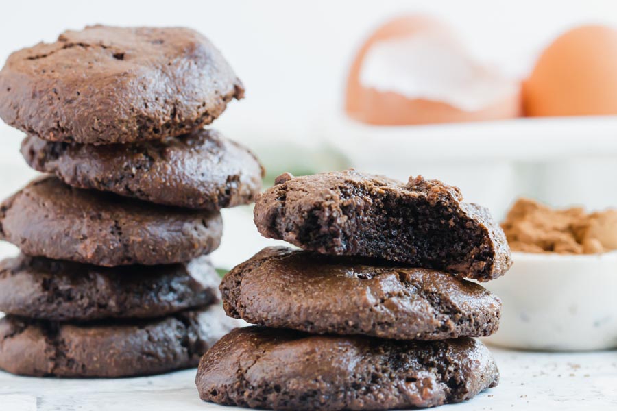 close up stack of mint chocolate cookies with eggs and cocoa powder