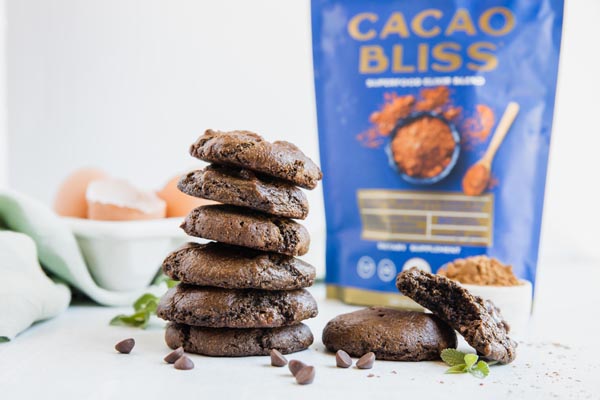 a stack of thin mint cookies with a blue bag of cacao bliss powder in the background