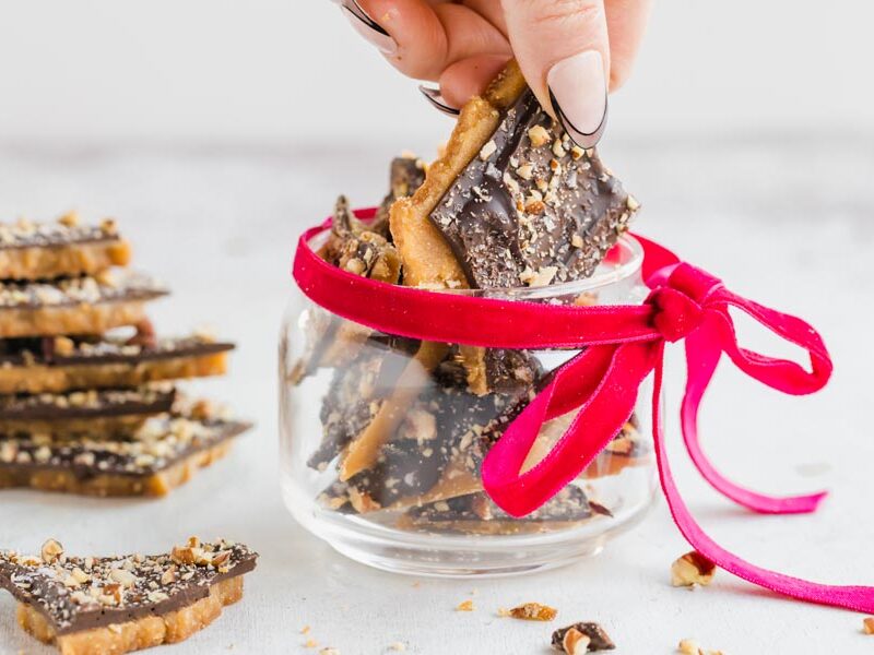 Grabbing a piece of toffee from a dish with a red bow around it.
