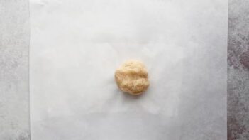 a ball of dough sitting on top of a white sheet of parchment paper