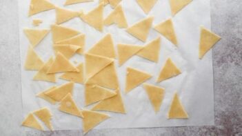 dough cut into triangle shapes on a white sheet of parchment paper