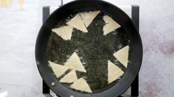 a bunch of triangle shaped chips frying in a skillet filled with oil