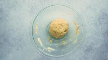 A clear, glass bowl with a large ball of dough inside.
