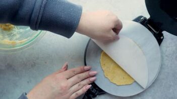 Peeling parchment paper off a flat tortilla.