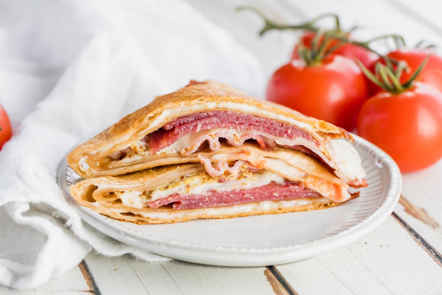 a wrap sandwich on a plate with tomatoes