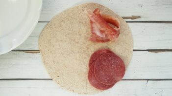 bacon and salami on top of a tortilla