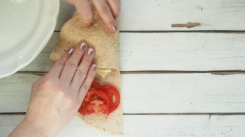 folding a tortilla wrap with tomatoes on one layer