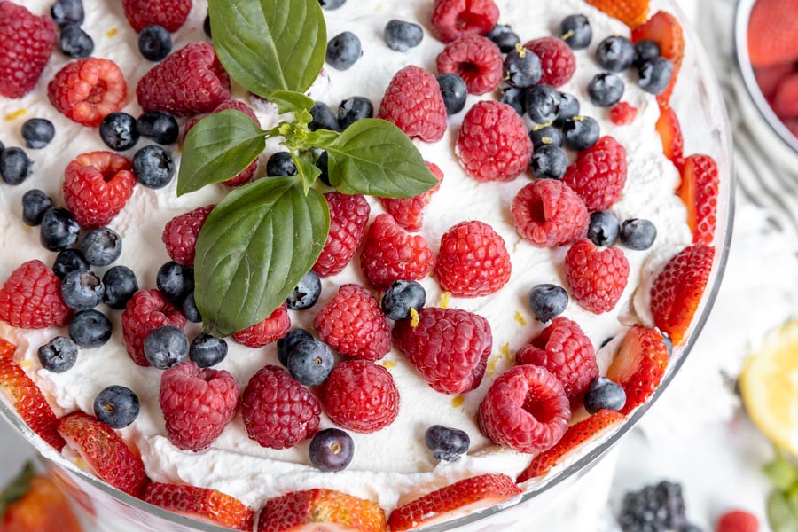 fruit berries scattered on top of whipped cream with basil on top