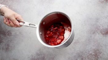 holding onto a saucepan with strawberry sauce inside