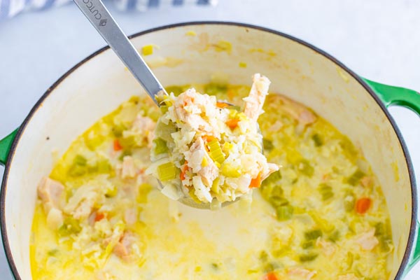 a wooden spoon holding a helping of keto turkey soup over a stock pot