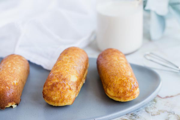 three twinkies on a plate with milk in the background