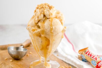 Keto Twix protein ice cream piled high in a sundae glass with sugar-free caramel sauce and buttery cookie crumbles.