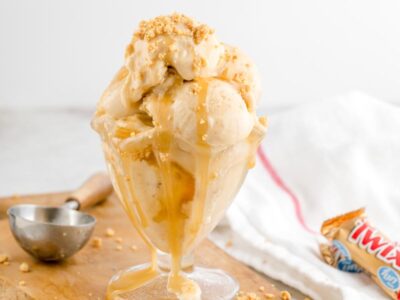 Keto Twix protein ice cream piled high in a sundae glass with sugar-free caramel sauce and buttery cookie crumbles.