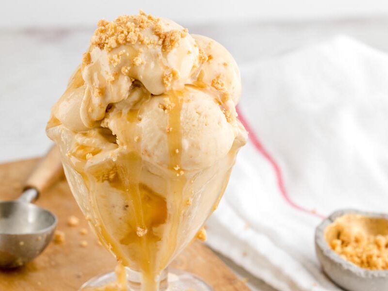 Close-up of creamy keto Twix ice cream topped with caramel drizzle and crunchy cookie crumbles.