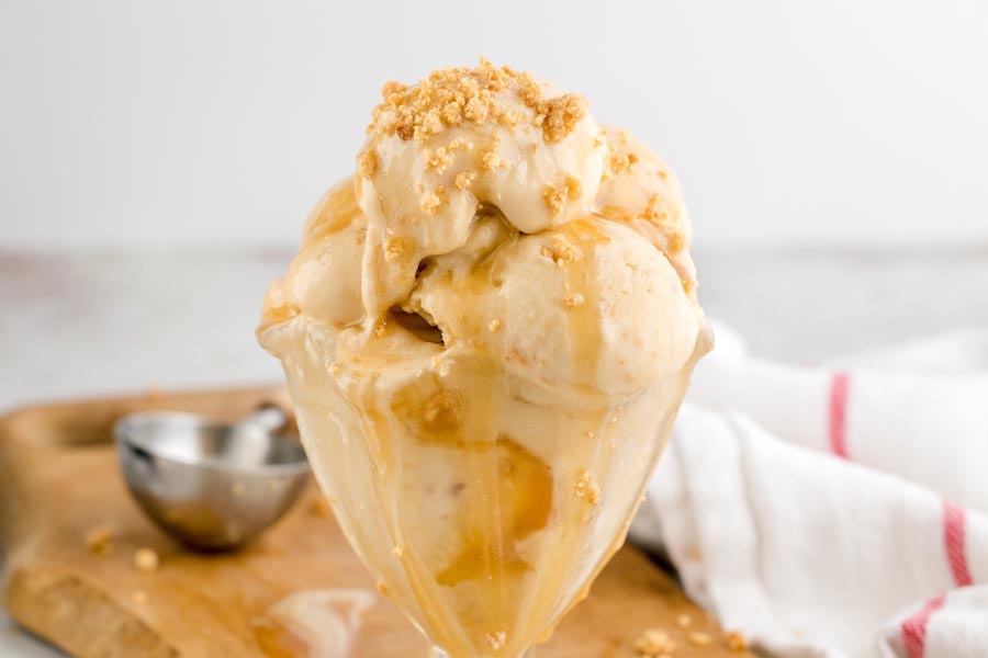 Close-up of scoopable keto Twix protein ice cream layered with gooey caramel and topped with cookie crumbles.