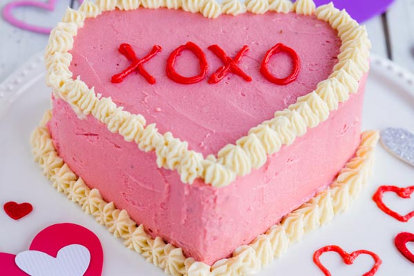 a conversation heart shaped cake with hugs and kisses written on it