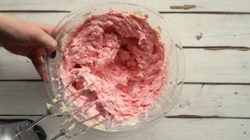 mixing pink frosting with a mixer