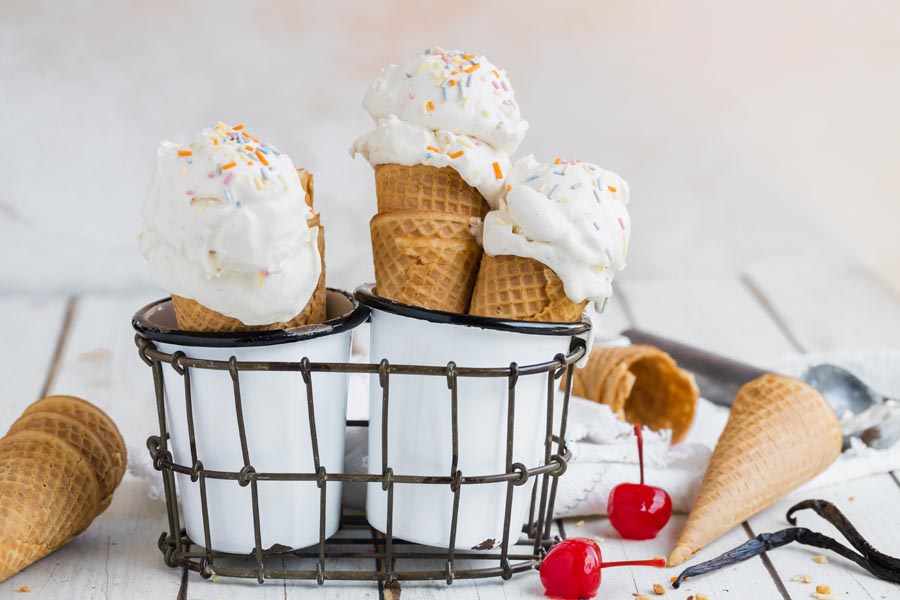 a container with white cups and cones in them while full cones and a scoop lie next to them