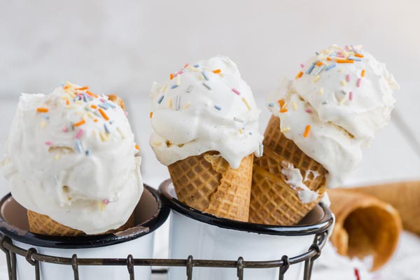 three ice cream cones with double scoop vanilla and sprinkles