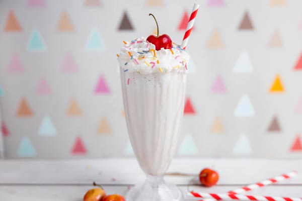 keto vanilla shake with whipped cream and cherries scattered around in a milkshake glass