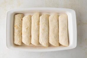 Unsauced enchiladas in a casserole dish.
