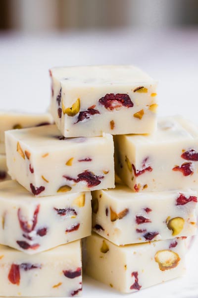 Close-up view of neatly stacked white chocolate fudge squares filled with cranberries and pistachios.