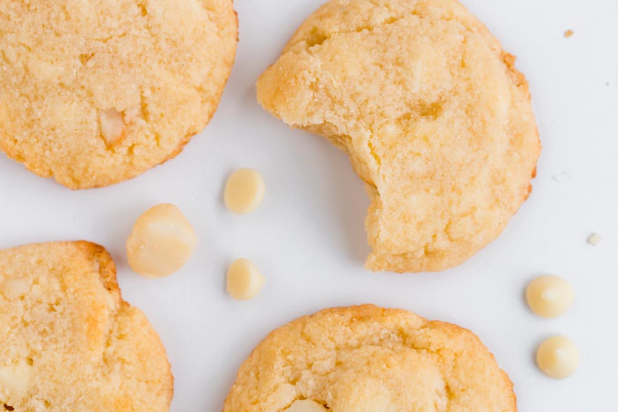 four cookies with white chips and nuts scattered around