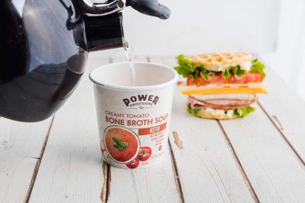 pouring hot water from a kettle into a portable keto tomato soup cup