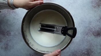 Holding the liner of an Instant Pot with a thermometer inside.