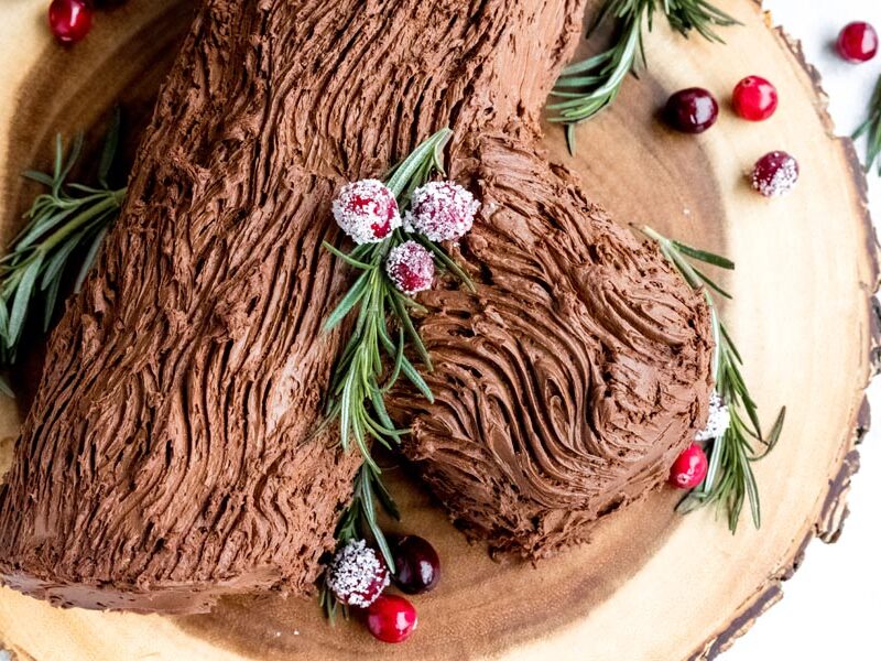 A buche de noel covered with chocolate frosting with decorated in a bark.