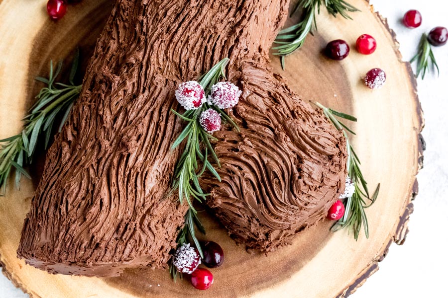 A buche de noel covered with chocolate frosting with decorated in a bark.