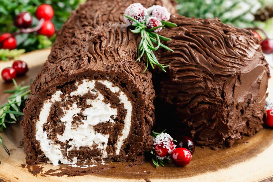 A slice of rolled chocolate cake cut off to show the cream and chocolate spirals swirl inside the cake.
