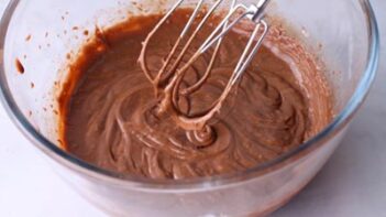 Electric mixer beaters over a brown chocolate ganache with a thick pudding consistency.